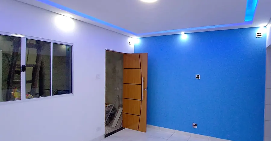 Sala com rebaixo de teto com fita de LED azul, spots embutidos e parede pintada de azul